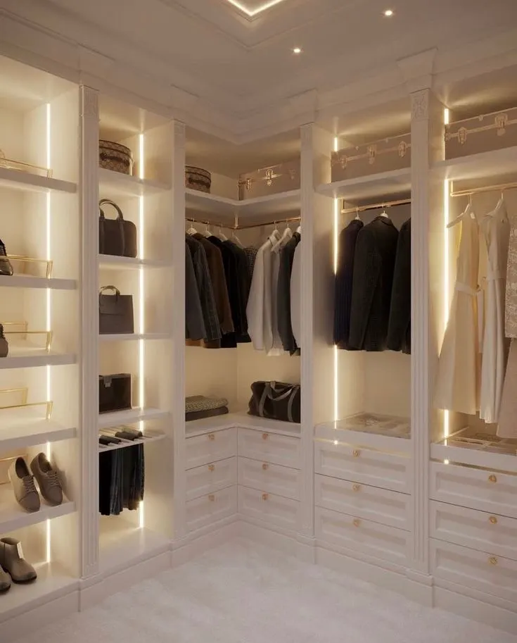 White color theme walk in closet with gold drawer knobs and dress hangers