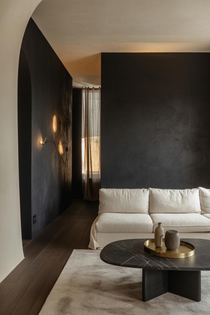 Modern architectural living room with nocturnal charcoal black feature wall (#1E1F22), ivory linen sofa, dark oak floors, black marble coffee table, and moody layered lighting.