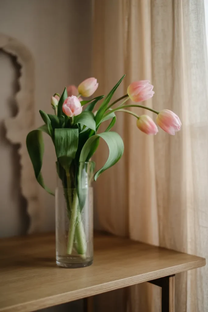 Minimal spring mono-floral arrangement with tulips in a tall narrow glass vase, styled in soft natural light with a clean modern aesthetic.
